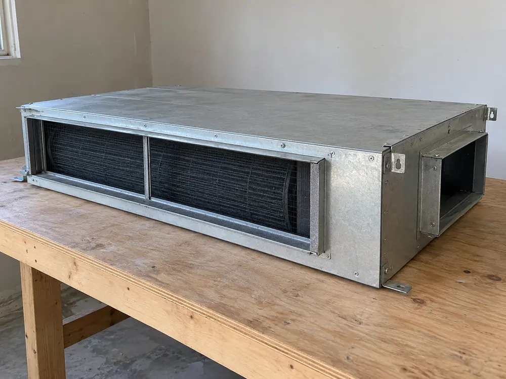 Uninstalled low-profile ducted indoor-unit illustration on a workbench.